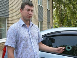 Андрей Стерхов показывает пулевое отверстие в стекле задней двери своего авто