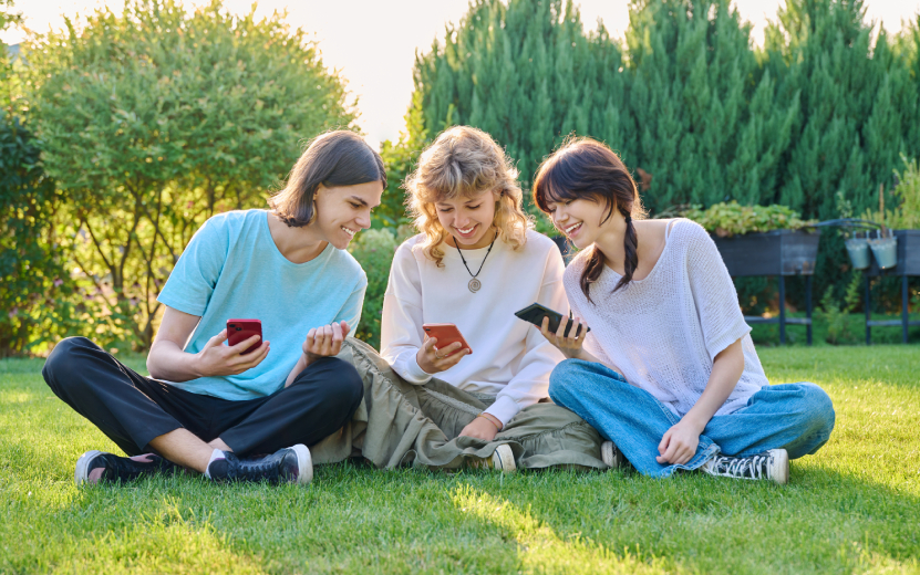 teenage-friends-sitting-on-the-grass-with-smartpho-2023-11-27-05-03-21-utc.jpg