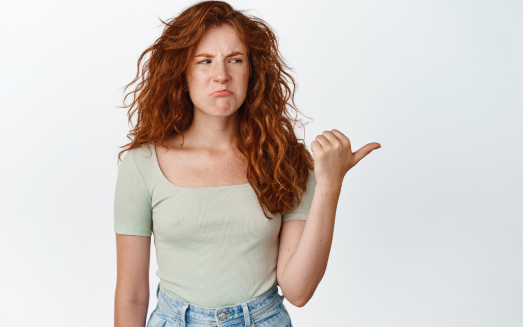 displeased-redhead-girl-sulking-frowning-with-dislike-pointing-looking-right-side-upset-standing-casual-tshirt-white-background (1).jpg