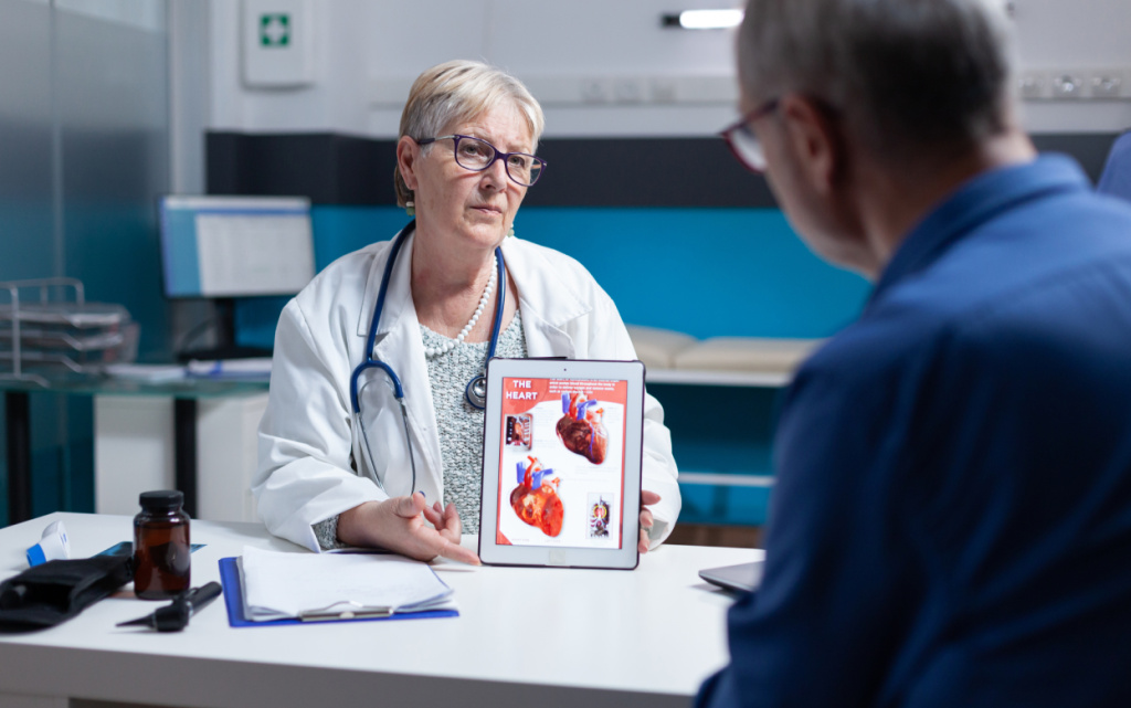 vrac-ob-asnaet-pacientu-kardiologiceskii-diagnoz-s-izobrazeniem-serdecnogo-organa-na-plansete-vrac-obsei-praktiki-pokazyvaet-celoveku-illustraciu-serdecno-sosudistoi-sistemy-i-anatomiceskogo-stroenia (1).jpg