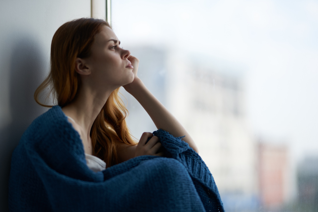 sad-woman-looking-out-window-wrapped-in-blanket-2026-03-24-06-20-07-utc.jpg