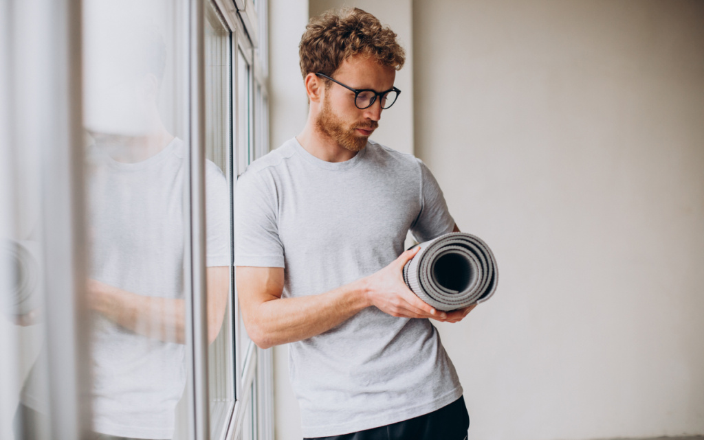 yoga-trainer-standing-with-mat-by-window (1).jpg