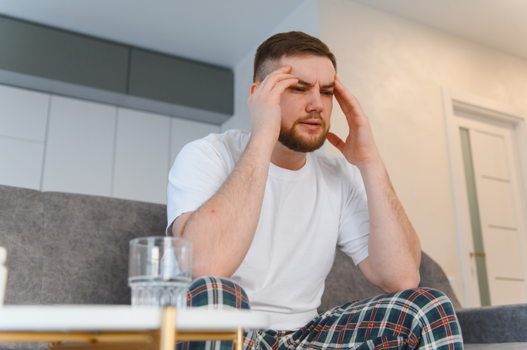 adult-man-with-headache-sitting-on-couch-2026-03-27-00-55-10-utc.jpg