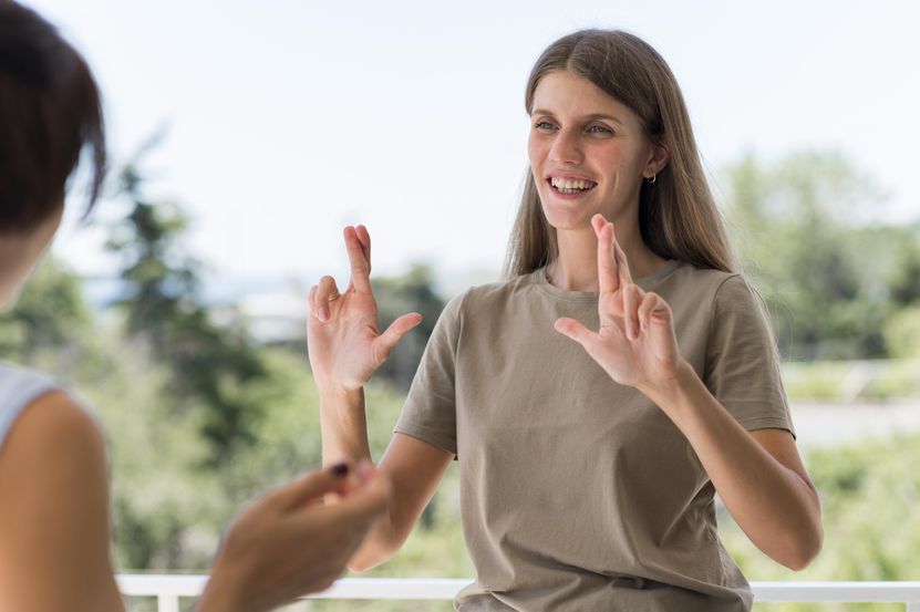 smiley-woman-communicating-through-sign-language-while-outdoors.jpg