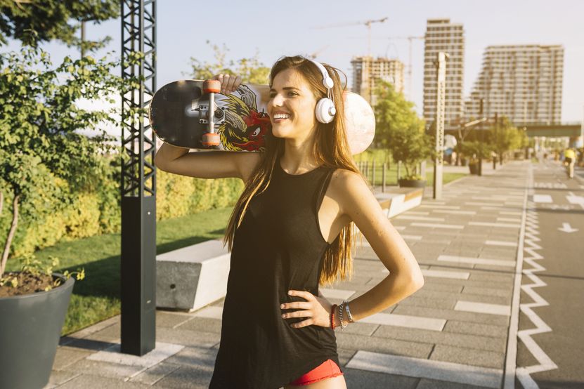 happy-young-woman-with-skateboard-standing-sidewalk.jpg