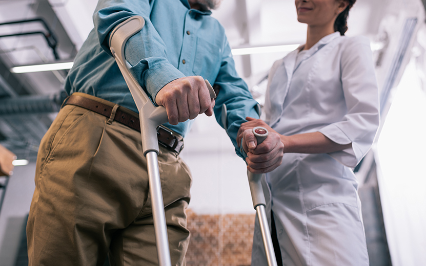 old-man-leaning-on-crutches-and-female-doctor-hand-2023-11-27-05-35-35-utc.jpg