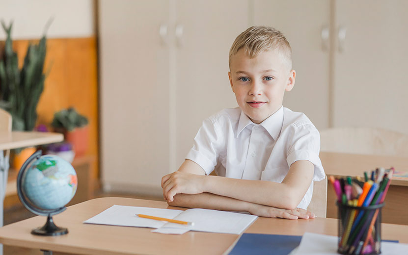 boy-sitting-with-hands-table-classroom.jpg