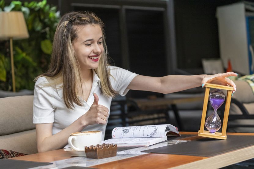 smiling-lady-holding-hourglass-gesture-thumb-up.jpg