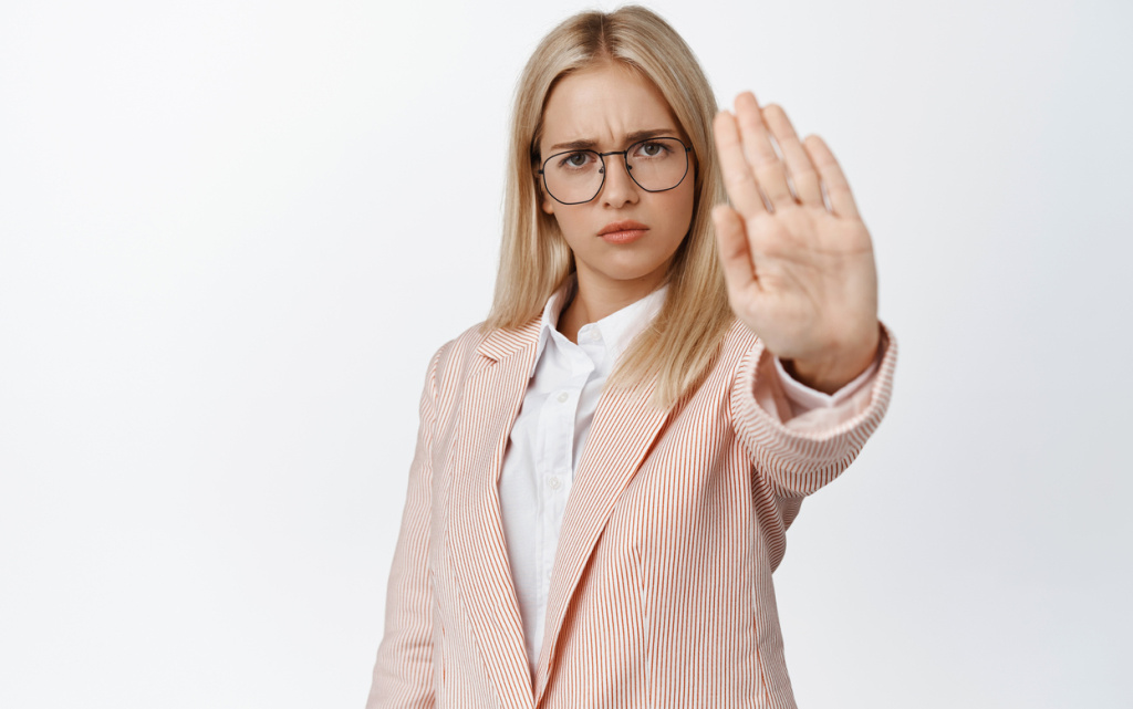 serious-female-entrepreneur-stretching-out-hand-stop-sign-prohibit-forbid-something-saying-no-standing-white-suit-glasses (1) (1).jpg