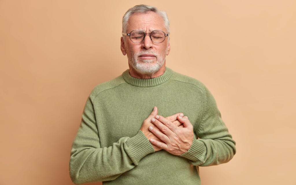 zrelyi-muzcina-prizimaet-ruki-k-serdcu-u-nego-problemy-s-serdecno-sosudistymi-zabolevaniami-on-stradaet-ot-serdecnogo-pristupa-i-bolit-v-grudi-s-zakrytymi-glazami-nuzdaetsa-v-pomosi-vracei-nosit-povsednevnyi-dzemp (1).jpg
