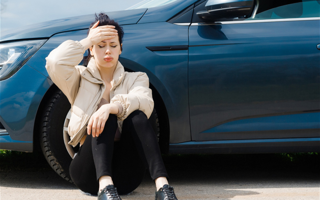 distressed-woman-sits-by-car-with-hand-on-head-2026-03-13-05-27-02-utc (1).jpg