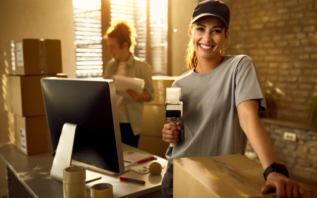 happy-courier-using-tape-dispenser-while-packing-boxes-delivery-looking-camera (1) (1).jpg