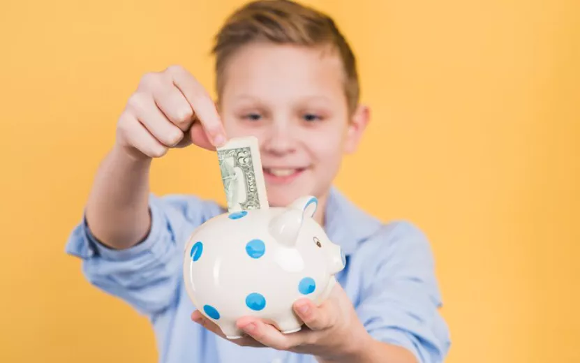 selective-focus-boy-inserting-currency-note-polka-dot-ceramic-piggy-bank-against-yellow-backdrop_23-2148089012.jpg