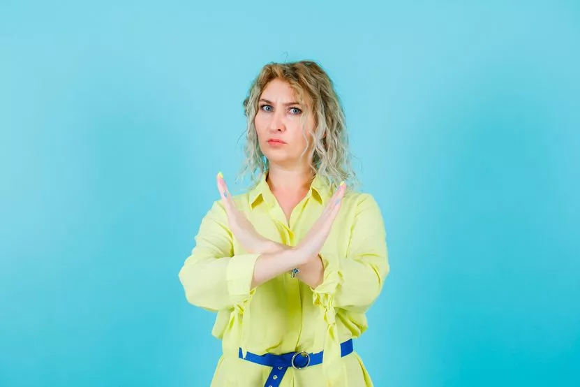 angry-blonde-woman-is-showing-stop-gesture-by-crossing-hands-blue-background.jpg