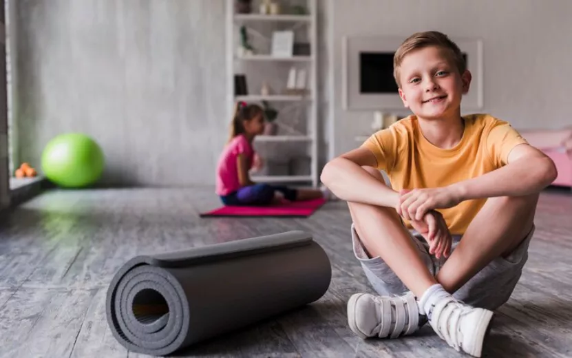 portrait-smiling-boy-sitting-near-rolled-up-exercise-mat_23-2148186387.jpg
