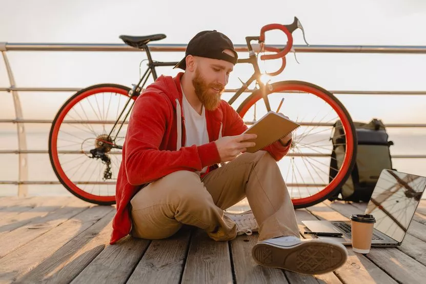 handsome-hipster-style-bearded-man-studying-online-freelancer-writing-making-notes-with-backpack-bicycle-morning-sunrise-by-sea-healthy-active-lifestyle-traveler-backpacker.jpg
