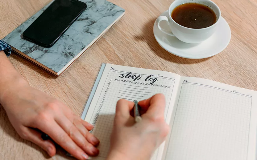 woman-hand-with-sleep-log-or-diary-on-table-how-t-2021-08-30-09-50-56-utc.jpg